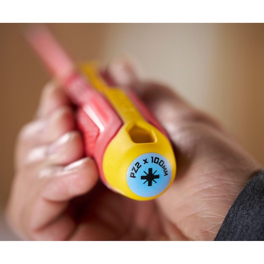 Close-up of a hand holding a STANLEY screwdriver, showing PZ2 x 100mm marking on yellow handle end.