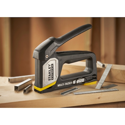 STANLEY FMHT70401-0 multi-tacker tool with staples on wooden surface, side angle.