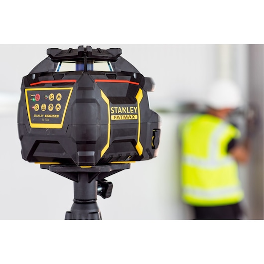 Stanley FMHT77447-1 laser level on tripod in indoor workspace, black and yellow design.