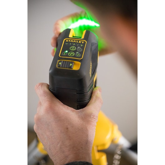STANLEY FMHT77597-1 green beam laser level in use, close-up held by hand.
