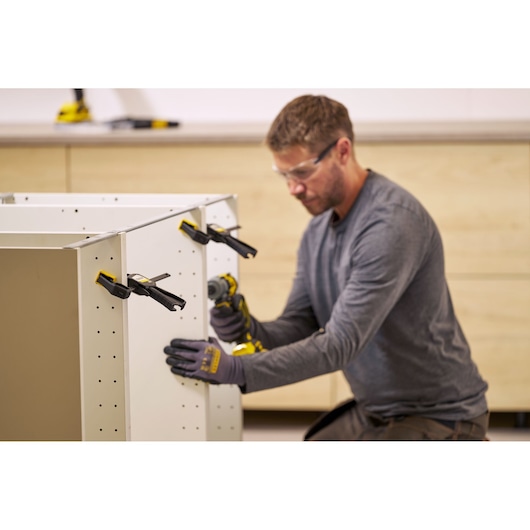 STANLEY FMHT83271-0 quick-adjust clamps used to hold white cabinet panels during assembly, workshop setting.