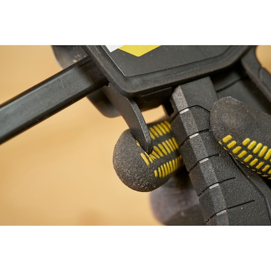 STANLEY FMHT83271-0 clamp close-up with gloved hand pressing trigger, photography product.