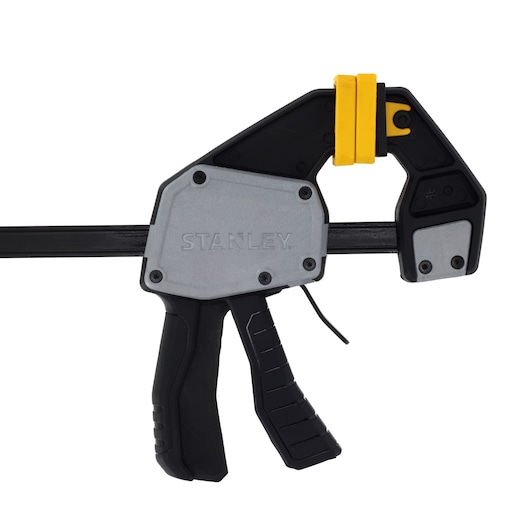 Photo of STANLEY FMHT83274-0 quick clamp with black handle, grey body, and yellow jaw, side angle, white background.