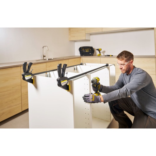 Photo of STANLEY FMHT83277-0 bar clamps securing a cabinet frame during assembly in a workshop setting.