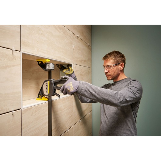Photo of STANLEY FMHT83280-0 clamp used to secure tiles during installation, person wearing gloves adjusting tiles.