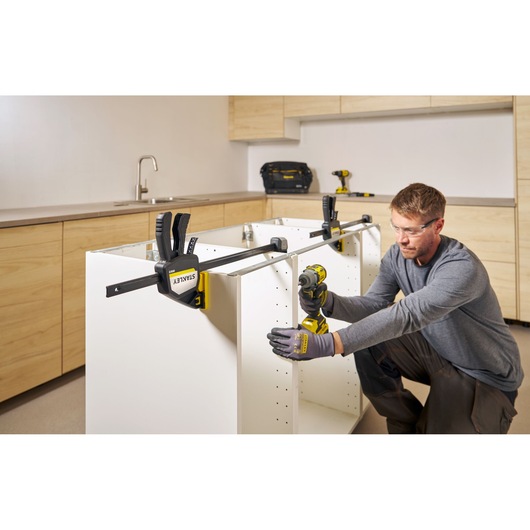 STANLEY FMHT83280-0 bar clamp used on white cabinet during assembly in kitchen setting.