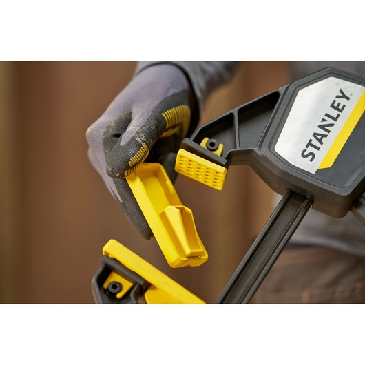 STANLEY FMHT83280-0 clamp with yellow removable jaw pad held by gloved hand, close-up photography.