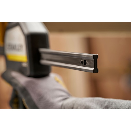 STANLEY FMHT83282-0 clamp photography, close-up of steel bar and gloved hand.