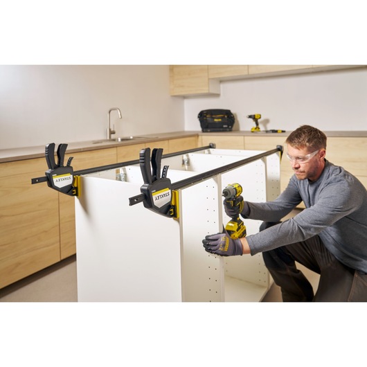 Photo of STANLEY FMHT83283-0 bar clamps securing a cabinet frame during assembly in a kitchen.