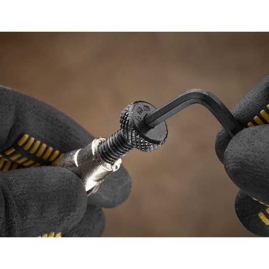 Gloved hands using an Allen key to tighten or loosen a knurled screw, close-up view of the action.