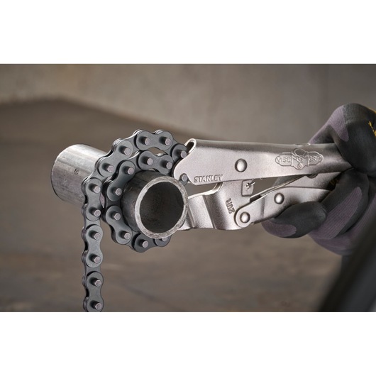 STANLEY chain locking pliers gripping a metal pipe, used for secure tightening and removal.