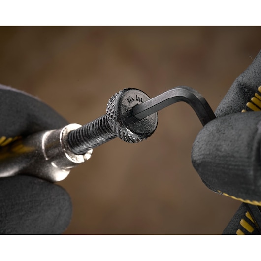 Close-up of a gloved hand using a hex key to tighten a metal screw.