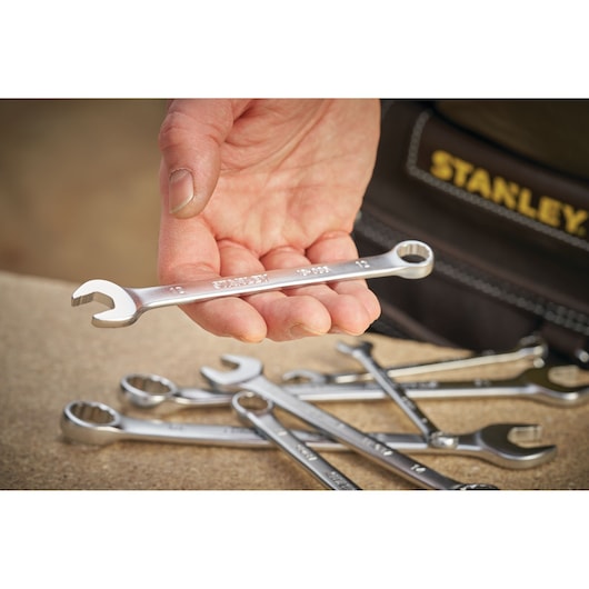 Photo of STANLEY FMMT13032-0 combination wrench held in hand, with several wrenches on work surface.