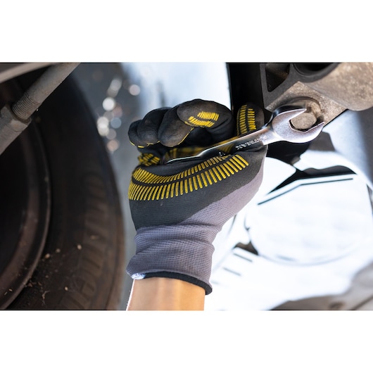 STANLEY FMMT13113-0 wrench used on bolt by gloved hand, close-up automotive repair.