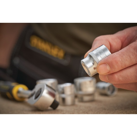 STANLEY FMMT17216-0 socket set with hand holding a silver socket, ratchet handle and sockets visible.