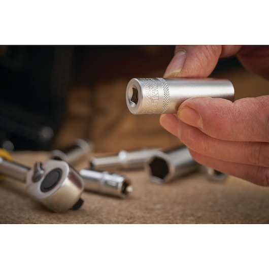 Photo of STANLEY FMMT17966-0 socket tool held by hand, with ratchet and other sockets on work surface.