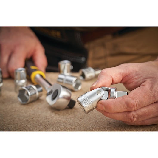 Photo of STANLEY FMMT17999-0 socket set with ratchet, hand holding silver socket, tabletop view.