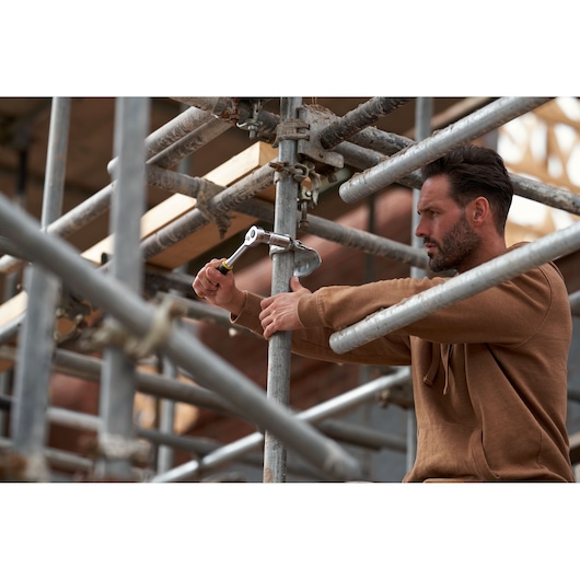 STANLEY FMMT82678-0 FATMAX 12120-Tooth Ratchet used on scaffolding by worker in brown hoodie.