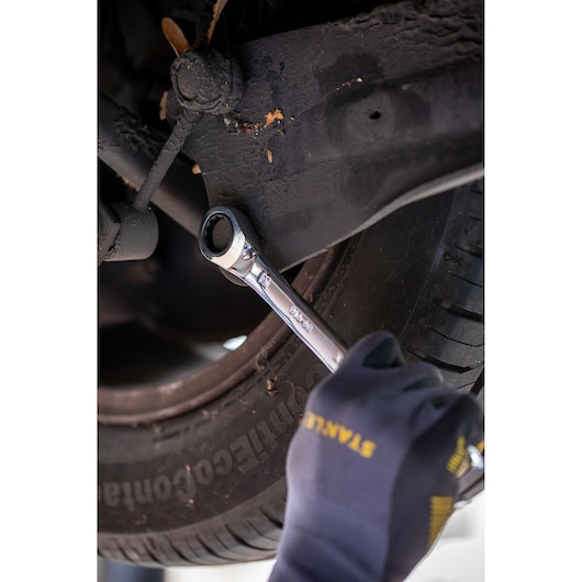 Photo of STANLEY FMMT82849-0 ratcheting wrench in use on car suspension bolt, mechanic wearing STANLEY gloves.