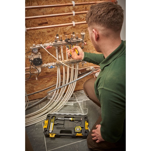 Stanley FMMT98106-1 toolkit in use by technician for plumbing, open case showing tools on floor.