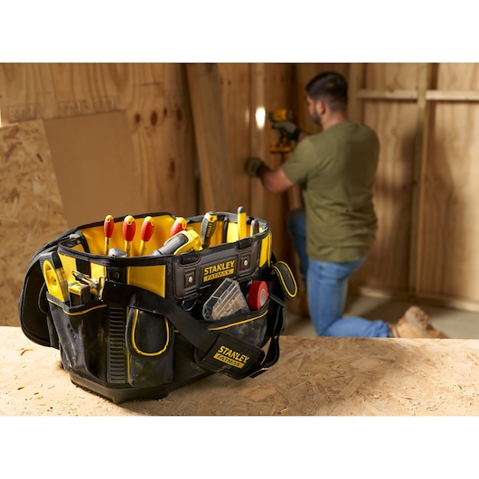 STANLEY FMST1-70749 tool bag in black and yellow, filled with hand tools, photographed on a workbench.