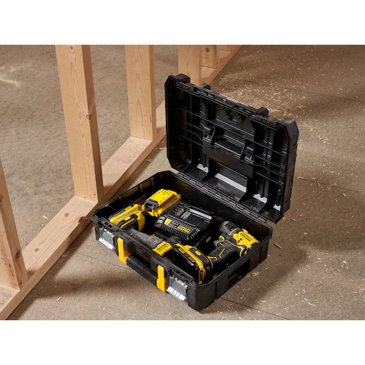 STANLEY FMST1-71966 black tool box with yellow latches, open, showing drill and accessories on workshop floor.