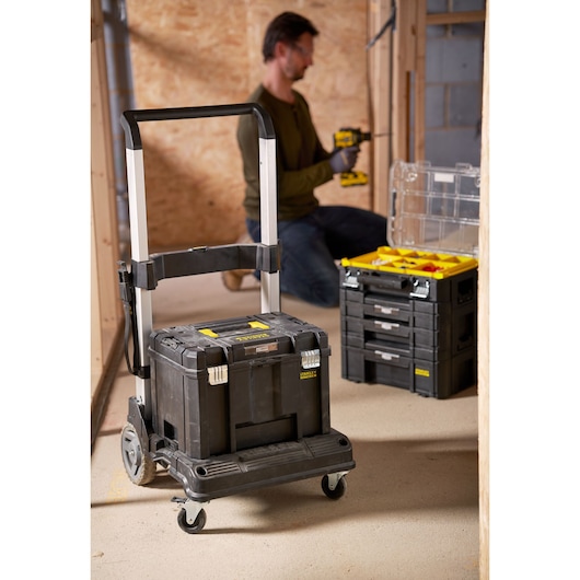 STANLEY FMST1-72363 black rolling tool box with telescopic handle in workshop setting.