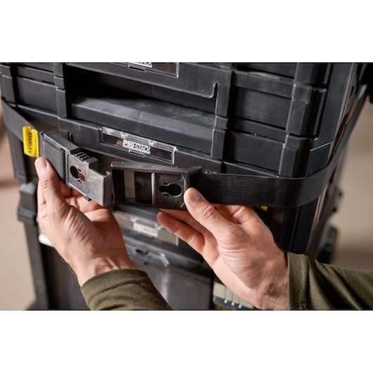 Photo of STANLEY FMST1-72363 tool storage strap with buckle securing black modular toolboxes, close-up view.