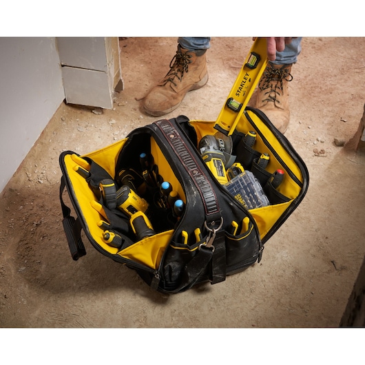 Photo of STANLEY FMST1-73607 tool bag on jobsite floor, open and filled with various hand and power tools.