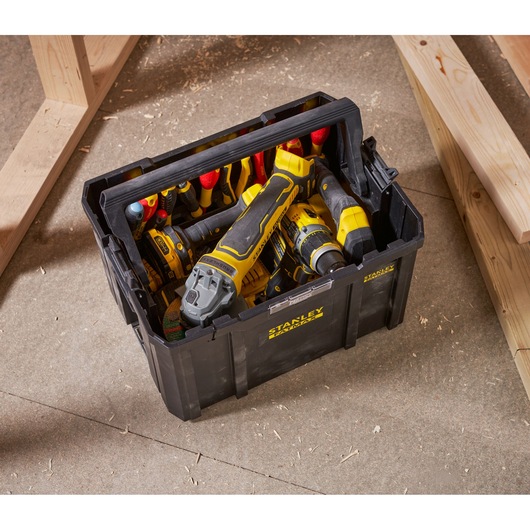 Stanley FMST1-75794 black tool box filled with yellow and black hand tools, top view, workshop setting.