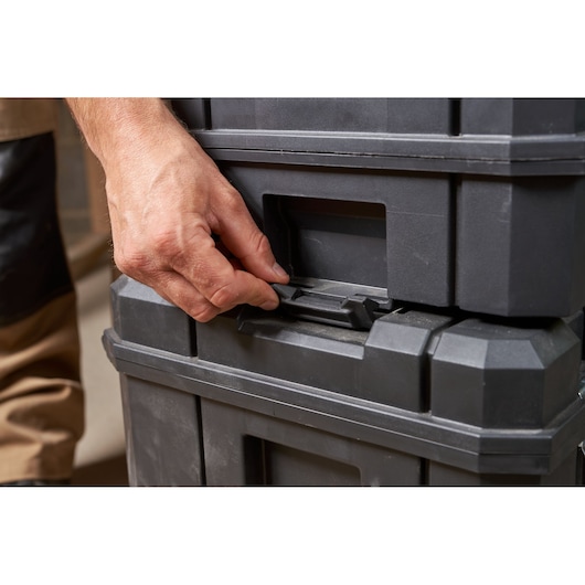 STANLEY FMST1-80103 black plastic toolbox latch being opened, close-up photo of stacked toolboxes.
