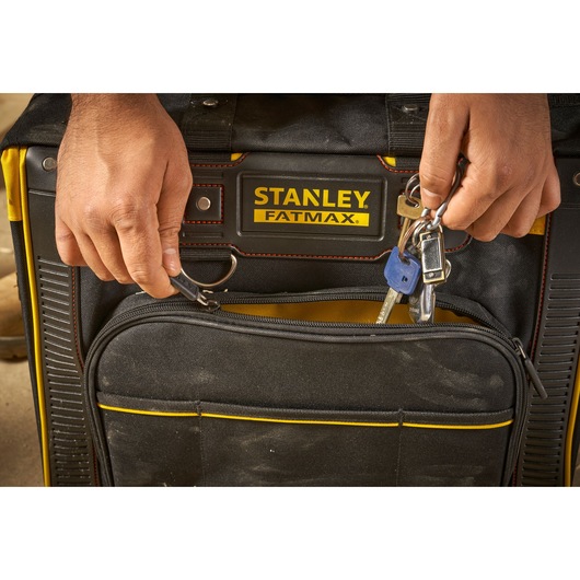 Photo of STANLEY FMST1-80148 Fatmax tool bag with hands attaching keys to the front key ring, close-up view.
