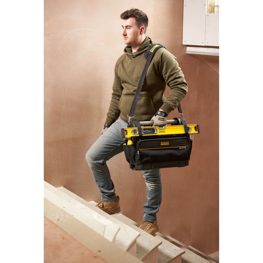 STANLEY FMST17626-1 tool bag with tools, carried by person on stairs, front angle photography.