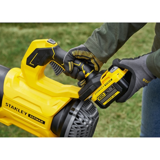STANLEY SFMCBL730M1 cordless blower close-up with gloved hand installing battery, outdoors.