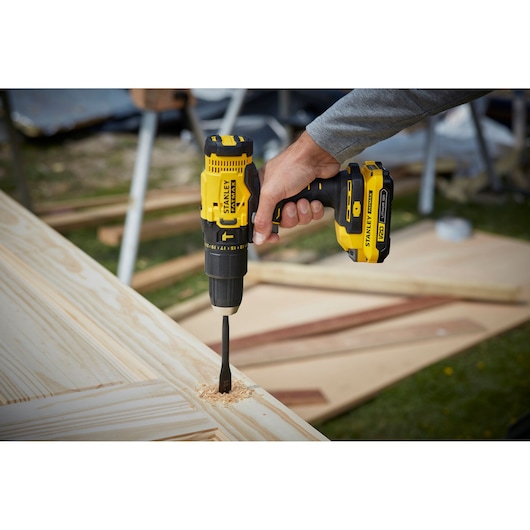 Photo of STANLEY SFMCD711C2K cordless drill used for woodworking, yellow and black design, side angle.
