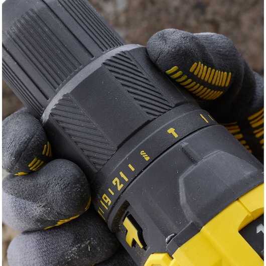 Close-up photo of STANLEY SFMCD711C2K cordless drill adjustment ring, black and yellow design, gloved hand grip.