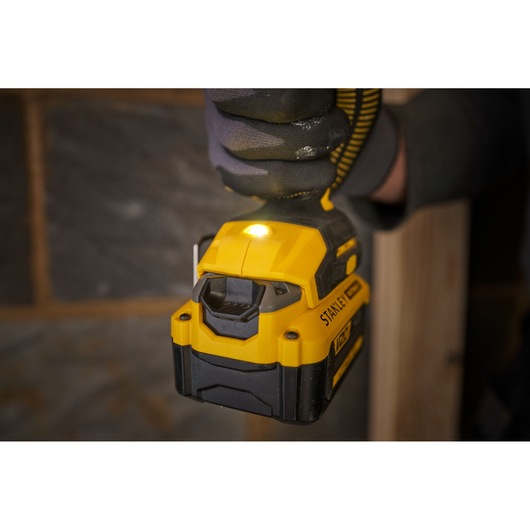 STANLEY SFMCD714D2T cordless drill close-up with LED light on, yellow and black design, in use indoors.