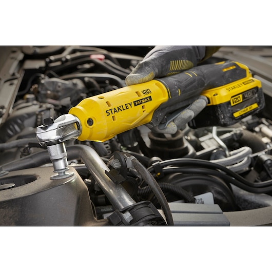 STANLEY SFMCF930B cordless ratchet being used on engine, yellow and black tool visible in close-up.
