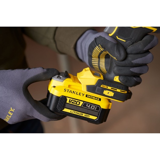 Photo of STANLEY SFMCF940M1 cordless drill with V20 4.0Ah lithium-ion battery being held with gloves.