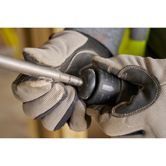 STANLEY SFMCH910M1T rotary hammer being adjusted by gloved hands, close-up photo.