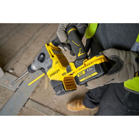 STANLEY SFMCH910M1T V20 cordless rotary hammer, close-up in worker’s gloved hands at job site.