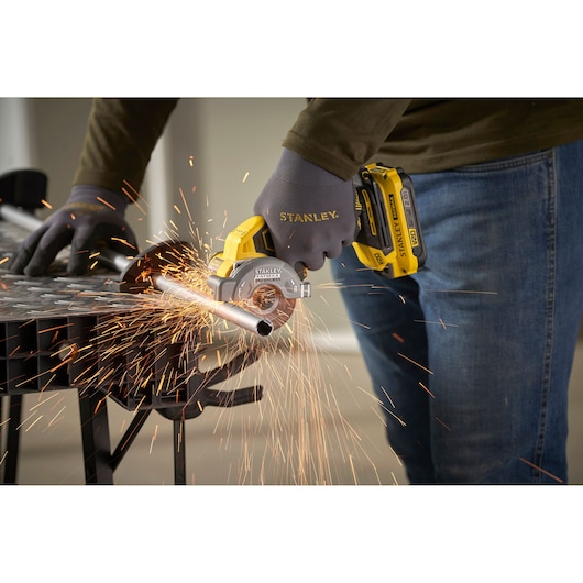STANLEY SFMCM300B compact cordless metal cutter in use, cutting metal pipe, close-up with sparks.
