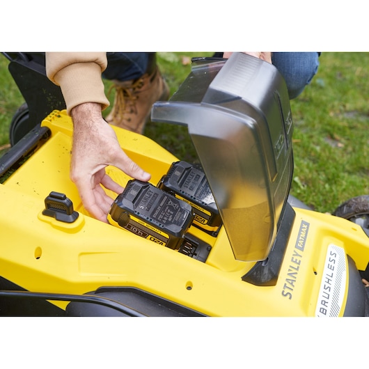 Photo of STANLEY SFMCMWS251B battery lawn mower with batteries being installed, close-up view.
