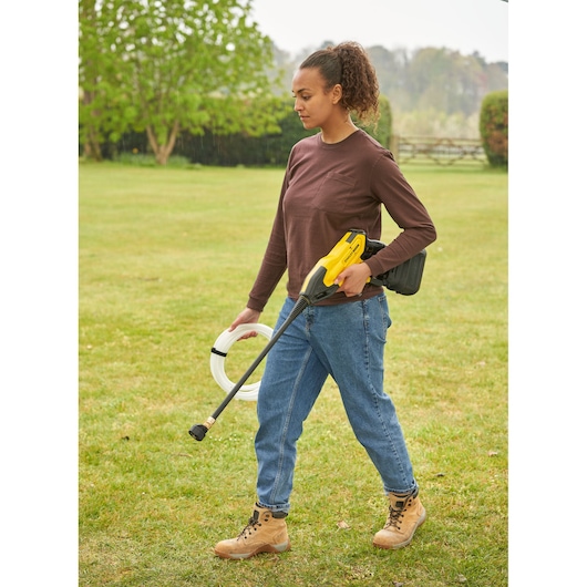 STANLEY SFMCPC93B portable pressure washer held by person outdoors with hose accessory, photography