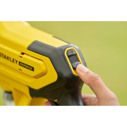 Photo of STANLEY SFMCPC93M1 photography tool, close-up of yellow and black body with finger on settings switch.