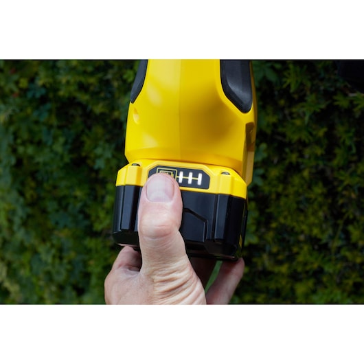 Photo of a STANLEY SFMCPH845B power tool battery pack held in hand outdoors.