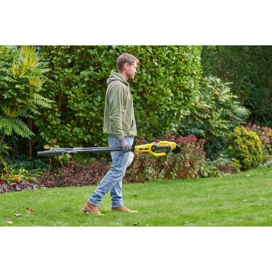 STANLEY SFMCPP632D1 pole pruner held by person outdoors, yellow and black tool in garden setting.