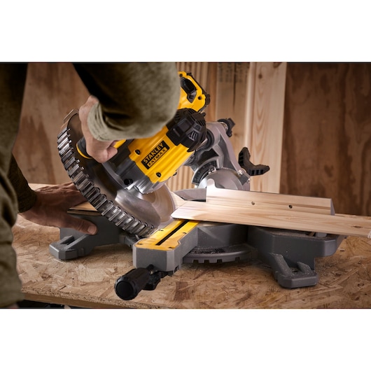 STANLEY SFMCS701M1 miter saw cutting wood, close-up angled view, yellow and black tool on workbench.