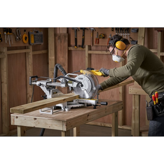 STANLEY SM1800 sliding mitre saw on workbench, used to cut wood in a workshop setting.
