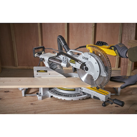 Photo of STANLEY SM1800 miter saw cutting wood, close-up view in workshop setting.